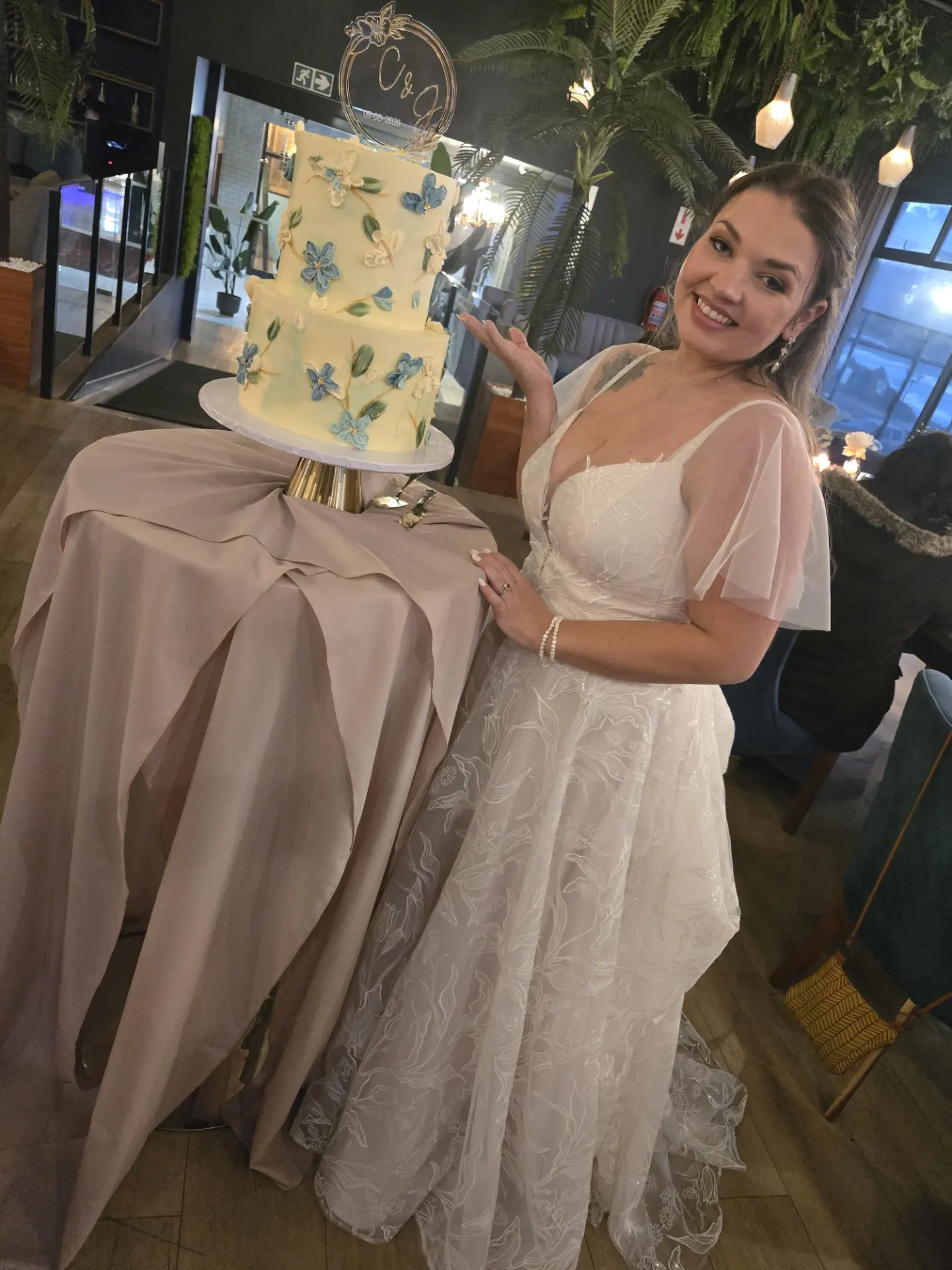 Corina beside a blue floral wedding cake