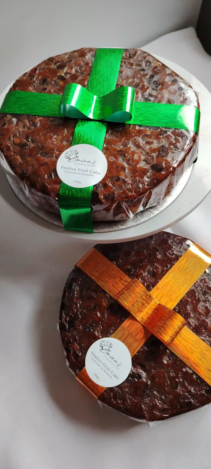 Two handmade festive fruit cakes wrapped with green and copper ribbons