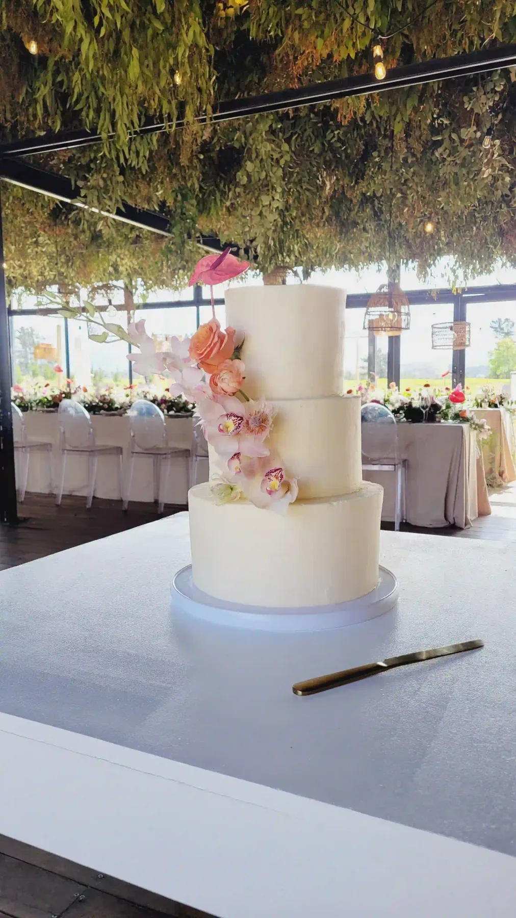 Three-tier wedding cake with peach roses and orchids